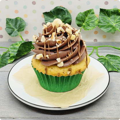 Detail van vanillecupcake met pralinévulling en chocoladetopping, gegarneerd met hazelnoten.