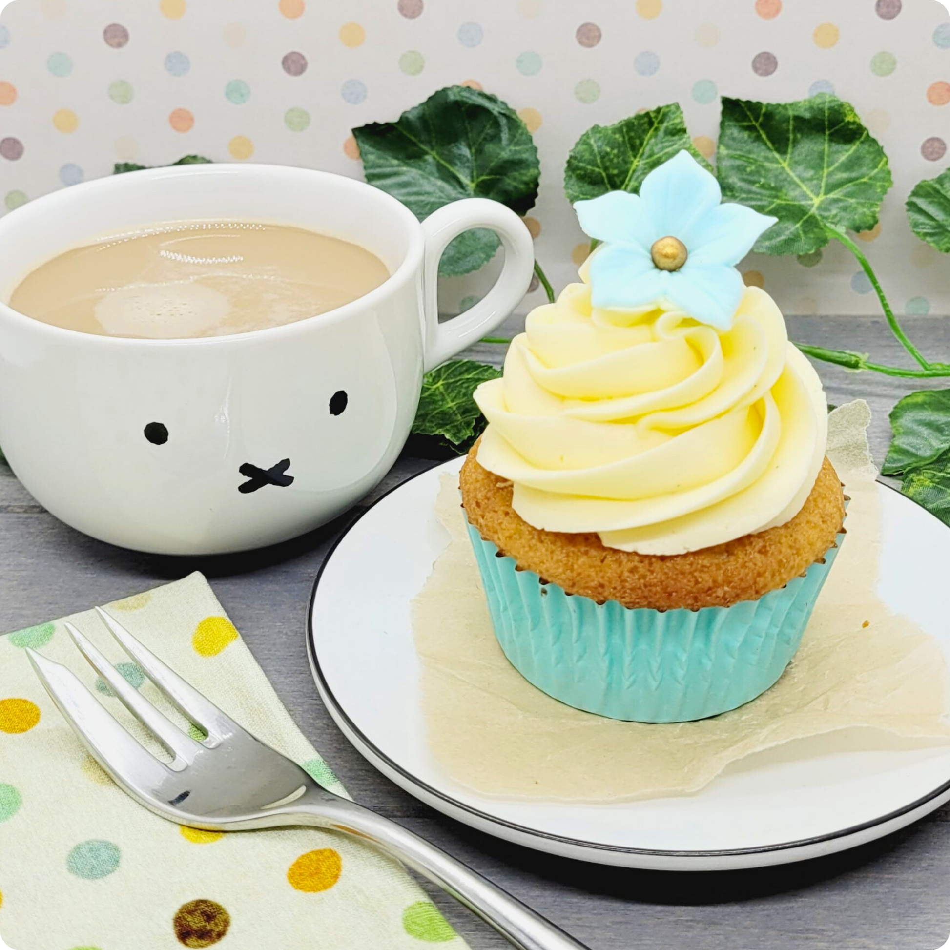 Vers gebakken vanillecupcake met romige botercrème, geserveerd op een bord met een kopje koffie.