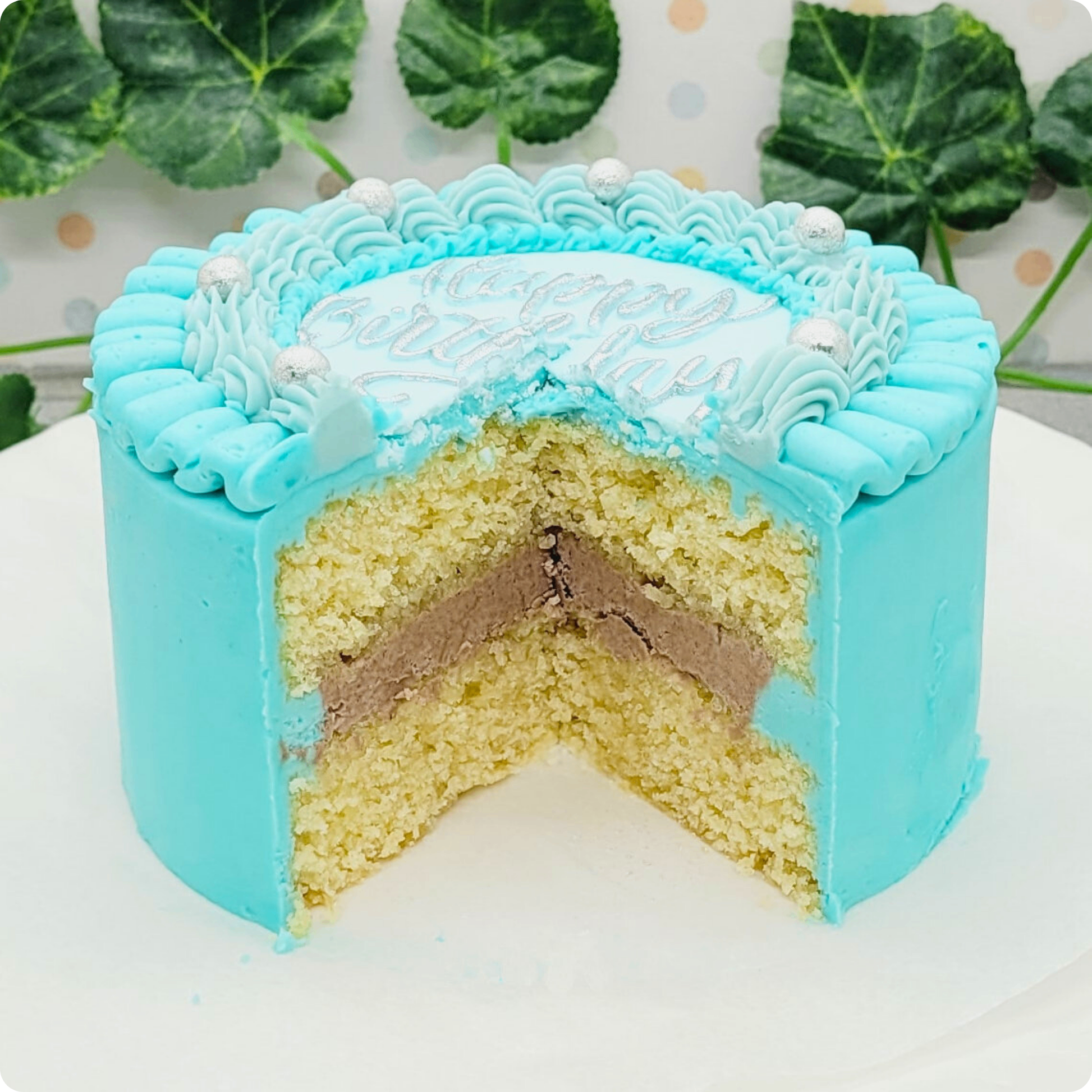 Aangesneden mini cake met vanillebiscuit en chocoladecrème, omhuld in blauwe crème