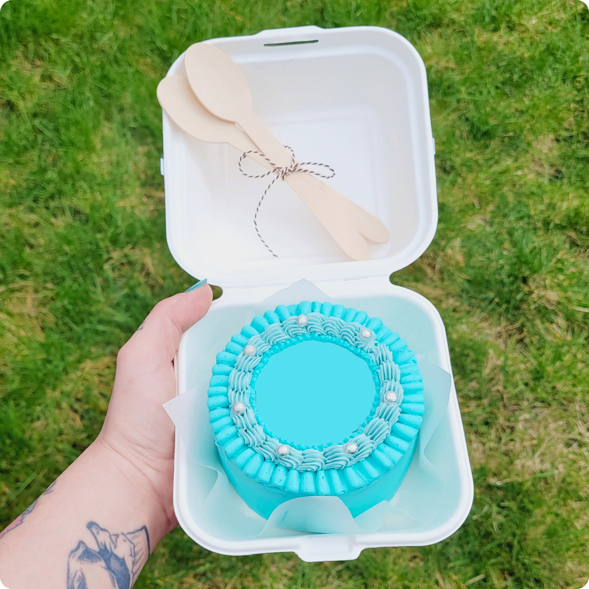 Bento cake in blauwe tinten met zilveren details, bovenaanzicht zonder tekst, in hand