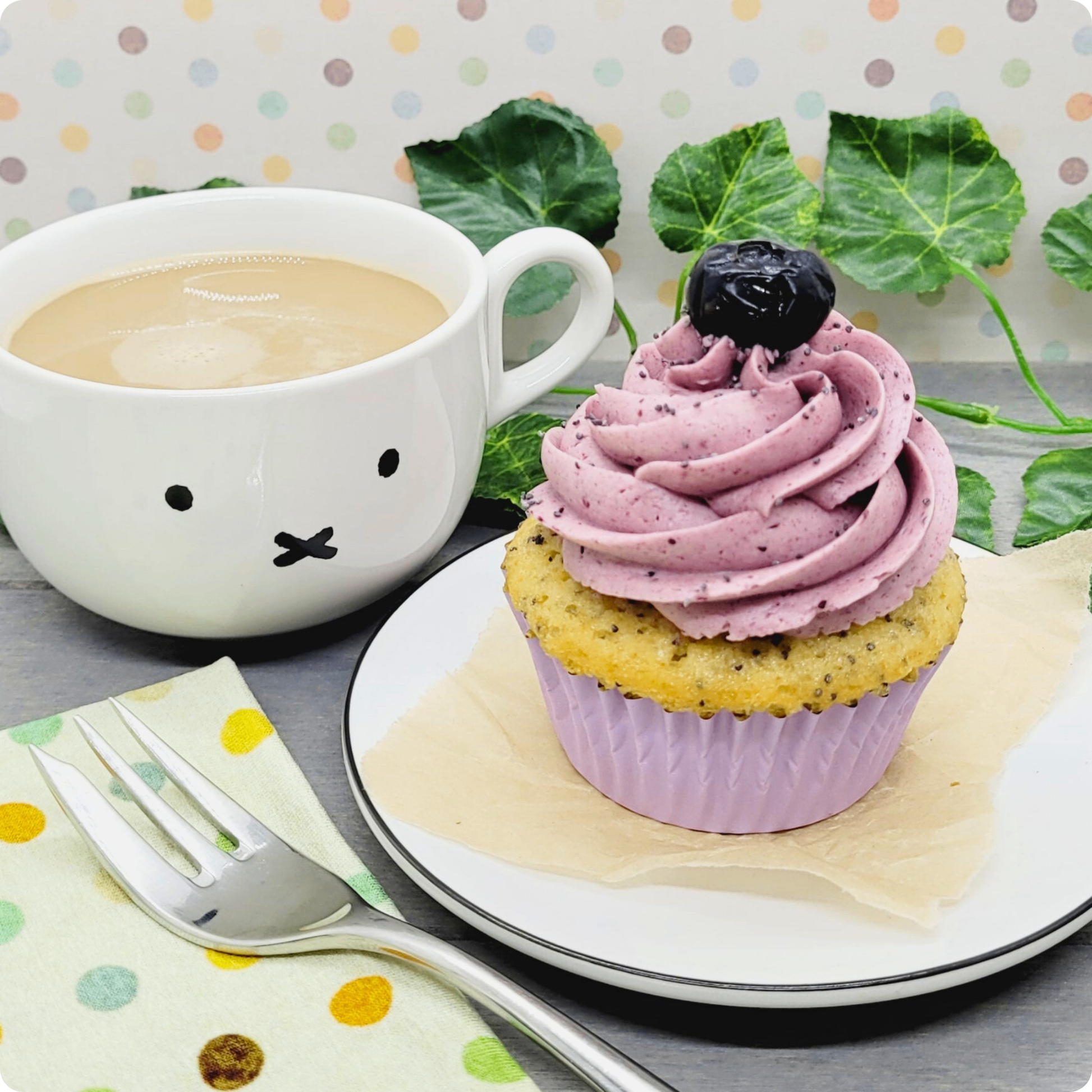 Poppy Blue Cupcake geserveerd op een bord met een kop koffie, perfect voor een zoete pauze.