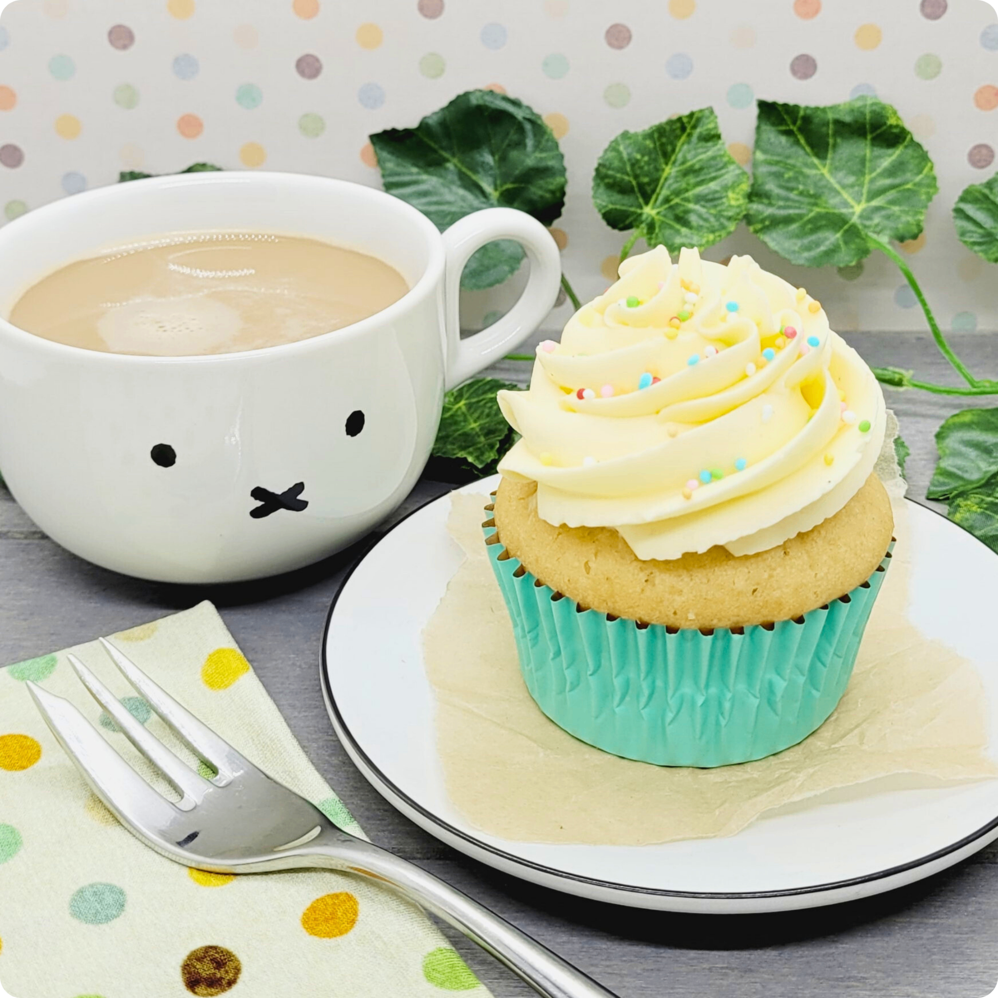 Vegan vanillecupcake geserveerd op een bord met een kop koffie, perfect voor een plantaardige zoete pauze.