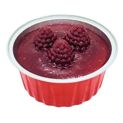 Bovenaanzicht van een mini New York cheesecake in een rood bakje met frambozen gelée