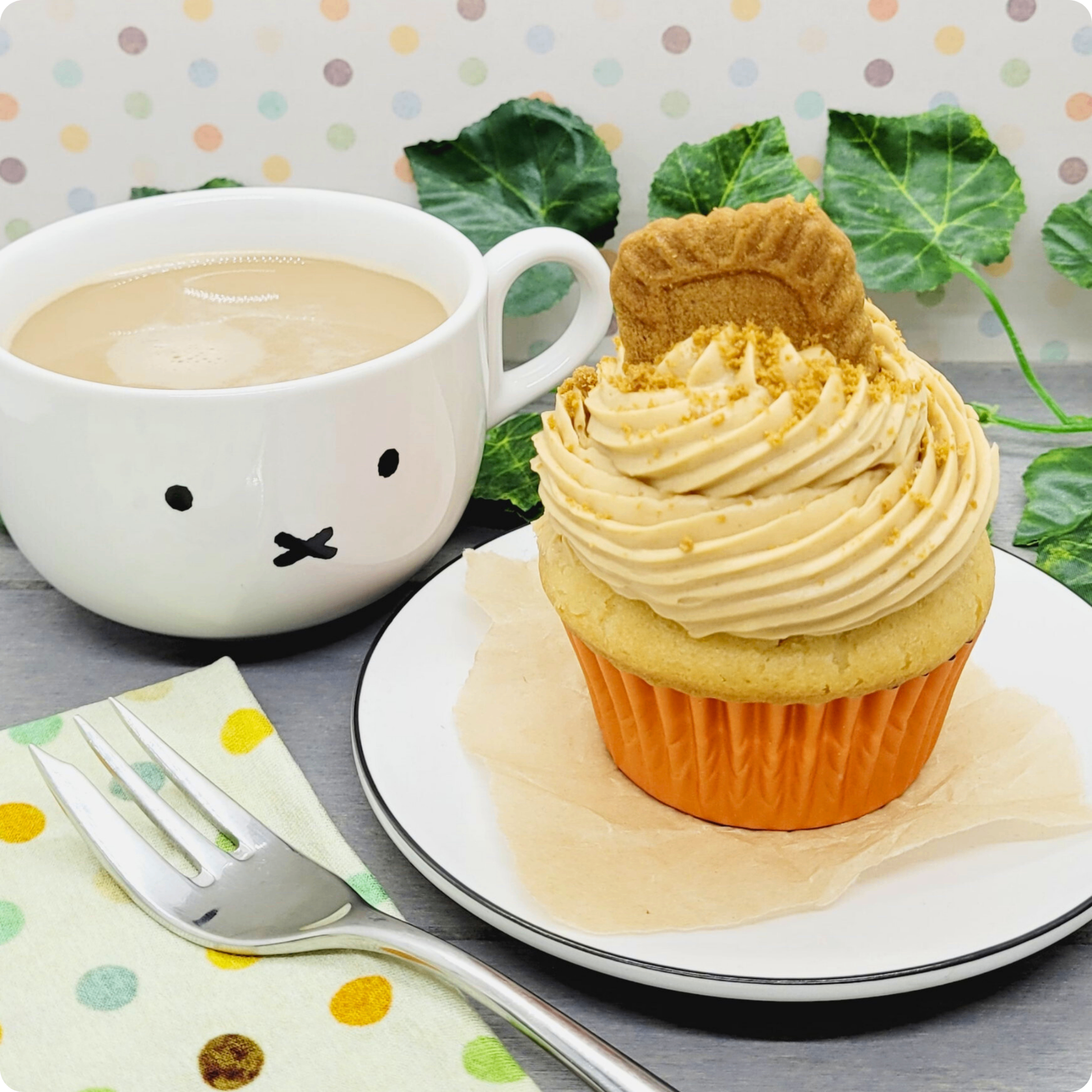 Vegan Lotus Biscoff Cupcake geserveerd op een bord met een kop koffie, een match made in heaven.